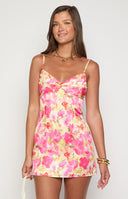 A model with blonde hair wears a floral mini dress in shades of pink
