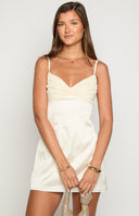 blonde model wearing a cream coloured satin mini dress with a contrast chiffon bust